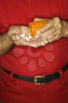 Royalty Free Photo of a Man Emptying a Pill Bottle into Hand