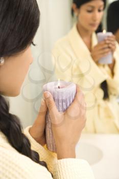 Royalty Free Photo of a Young Woman Holding a Lit Candle in Front of a Mirror