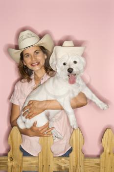 Royalty Free Photo of a Woman Holding a Terrier Dog Wearing Cowboy Hats