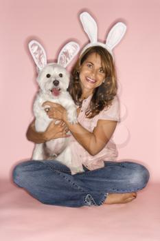 Royalty Free Photo of a Woman and a White Terrier Dog Wearing Rabbit Ears