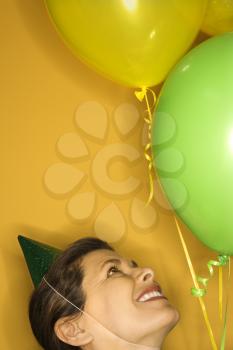 Royalty Free Photo of a Woman Wearing a Party Hat Holding Balloons