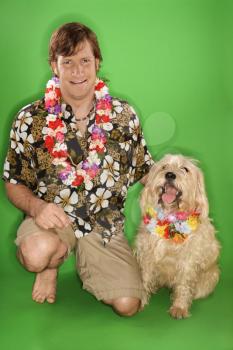 Royalty Free Photo of a Man Kneeling With a Dog Wearing a Lei