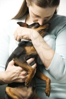 Royalty Free Photo of a Woman Holding and Kissing a Miniature Pinscher Dog