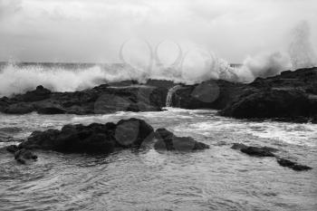 Landscape shot of waves crashing into rocky Maui Hawaii coast.