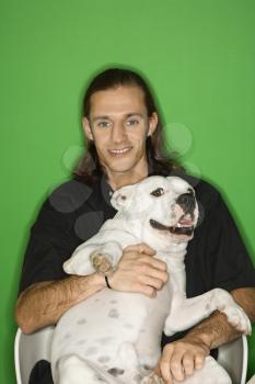 Royalty Free Photo of a Young Man Holding a White Pit Bull Dog on His Lap