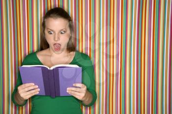 Royalty Free Photo of a Woman Reading a Book and Making an Expression