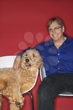 Royalty Free Photo of a Man Sitting With a Golden Doodle Dog
