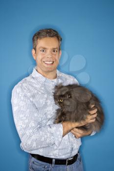 Royalty Free Photo of a Man Standing Holding a Persian Cat