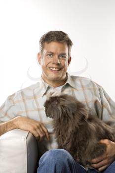 Royalty Free Photo of a Man Sitting Holding a Persian Cat