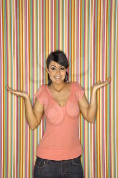Young adult female Caucasian shrugging on striped background.