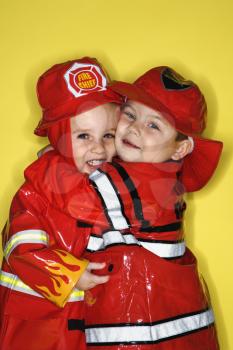 Royalty Free Photo of Twin Boys Dressed as Firemen Hugging 