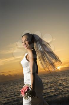 Royalty Free Photo of a Bride Holding a Bouquet on the Beach