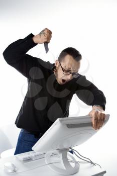 Royalty Free Photo of a Man with Tattoos and Piercings Stabbing the Computer With a Knife