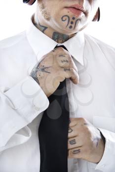 Royalty Free Photo of a Man With Tattoos and Piercings Adjusting Necktie