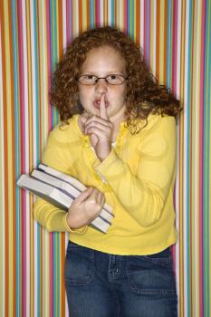 Royalty Free Photo of a Girl Holding Books and a Finger to Her Lips