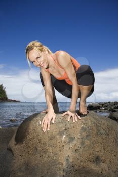 Royalty Free Photo of a Woman Squatting on a Large Rock