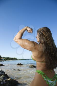Royalty Free Photo of a Female Bodybuilder in a Bikini Flexing Her Bicep on a Maui Beach