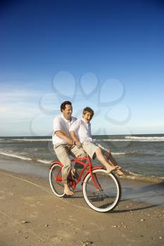 Royalty Free Photo of a Father Riding a Bike With His Son on the Handlebars 
