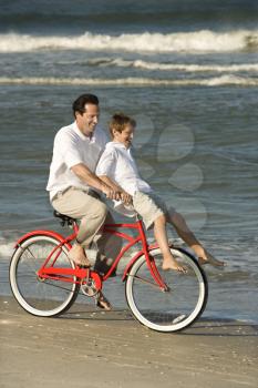 Royalty Free Photo of a Father Riding a Bike With His Son on the Handlebars 