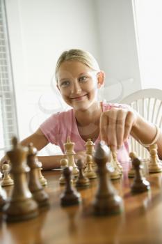 Royalty Free Photo of a Preteen Girl Playing Chess Smiling