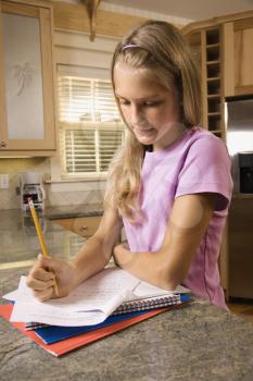 Royalty Free Photo of a Preteen Girl Doing Homework at a Kitchen Counter