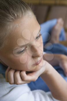Royalty Free Photo of a Preteen Girl With Chin in Hand Looking Down