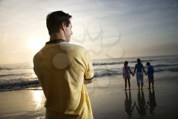 Royalty Free Photo of a Father Watching His Family on a Beach