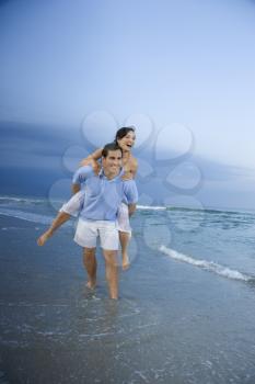 Royalty Free Photo of a Man Giving a Woman a Piggyback on the Beach