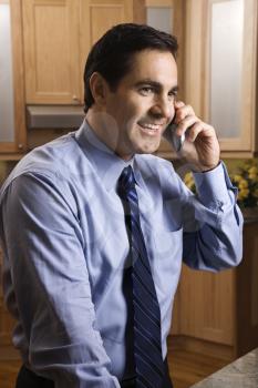 Royalty Free Photo of a Man Smiling and Holding a Cellphone While Standing in a Kitchen