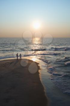 Aerial view of couple holding hands on beach in Bald Head Island, North Carolina at sunset.