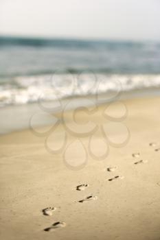 Royalty Free Photo of a Sandy Coastline with Footprints and Waves