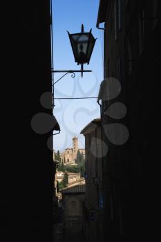 Royalty Free Photo of a Street Lamp and Siena Buildings Seen Through a Darkened Alley