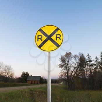 Royalty Free Photo of a Circular Yellow Railroad Grade Crossing Sign in Rural Setting