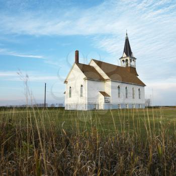 Royalty Free Photo of a Small Rural Church in a Field With Chipped Wood Siding