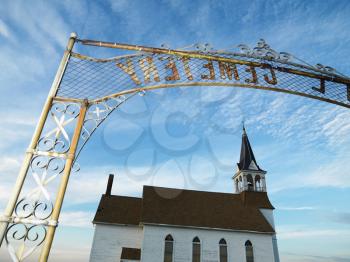 Royalty Free Photo of a Metal Cemetery Entryway With a Small Church