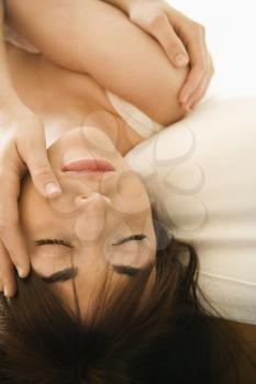 Royalty Free Photo of a Woman Lying on a Bed With Her Head Hanging Over With Eyes Closed