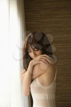 Royalty Free Photo of a Pretty Young Woman Standing by Sunlit Window