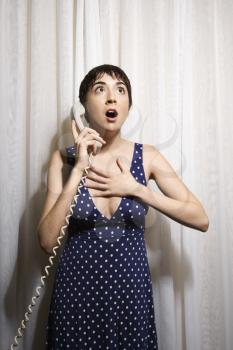 Royalty Free Photo of a Woman Holding a Telephone Receiver to Her Ear Looking Shocked