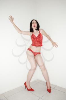 Caucasian young adult woman in lingerie making facial expression and gesturing.