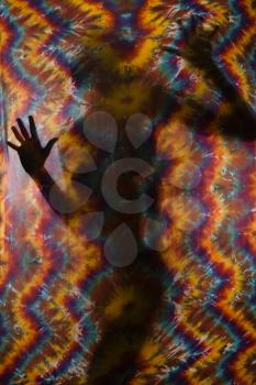 Royalty Free Photo of a Woman Silhouetted Behind a Tye-dye Fabric