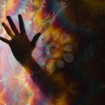 Royalty Free Photo of a Hand Silhouetted by Tye Dye Fabric