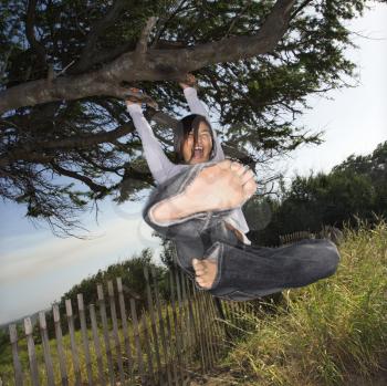 Royalty Free Photo of a Girl Holding on to a Tree and Kicking 