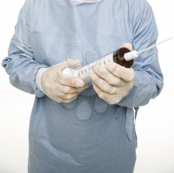 Royalty Free Photo of a Man Wearing Scrubs and Holding an Over-sized Syringe