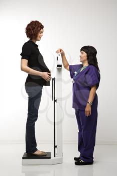Royalty Free Photo of a Pregnant Woman Being Weighed by a Nurse