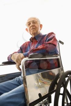 Low-angle view of Caucasion elderly man sitting in wheelchair looking down at viewer.