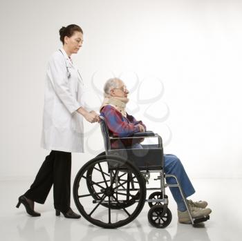 Royalty Free Photo of a Female Doctor Pushing an Elderly Male With a Neck Brace in a Wheelchair