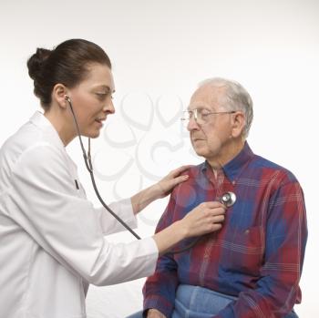 Royalty Free Photo of a Doctor Holding A Stethoscope to an Older Man's Heart