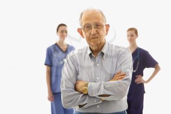 Royalty Free Photo of an Elderly Man in the Foreground With Two Female Medical Practitioners 