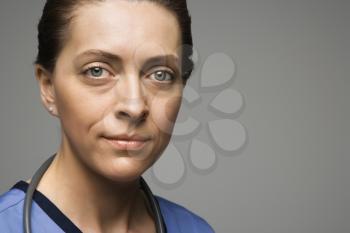 Head shot portrait of Caucasian woman doctor against gray background.