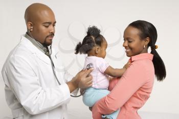 Royalty Free Photo of a Pediatrician Examining a Baby Girl Being Held by Her Mother